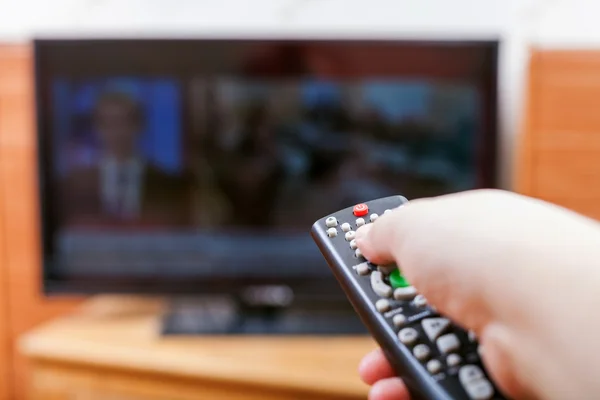 Hand switches TV channels with news — Stock Photo, Image