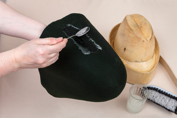 hatter applies an adhesive a felt hood for shaping