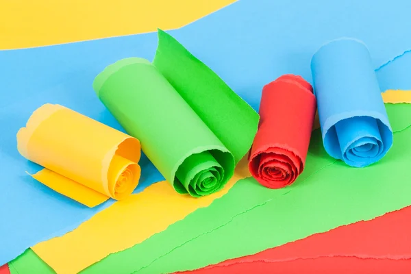 Rolled colour paper on sheets of torn paper — Stock Photo, Image