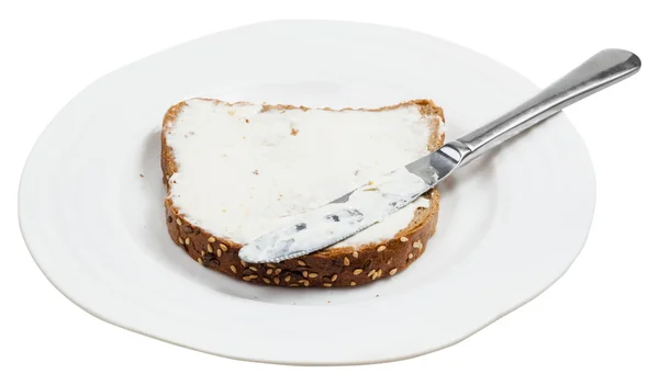 Pane di grano con formaggio spalmato e coltello sul piatto — Foto Stock