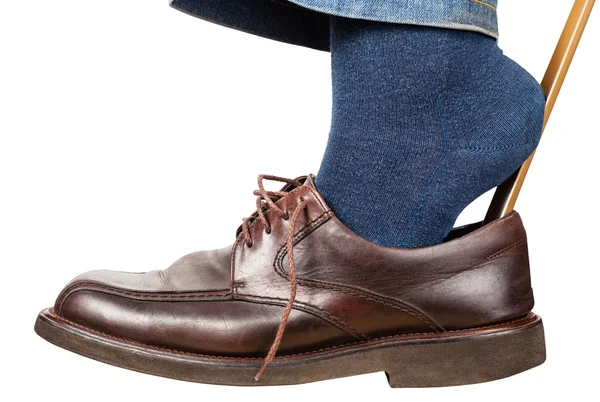 Man puts on brown shoes using shoe horn isolated — Stock Photo, Image