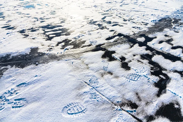 Footprints in snow and crack in ice on frozen lake — Stock Photo, Image