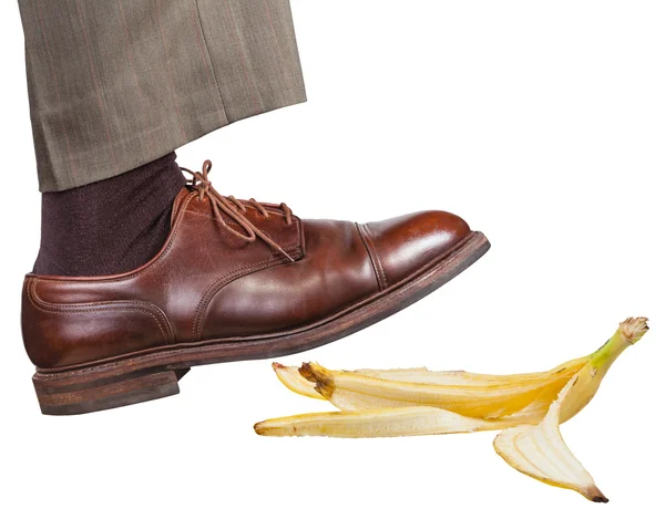 Bein im rechten braunen Schuh rutscht auf Bananenschale — Stockfoto