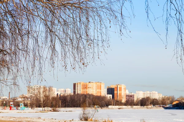 Lago congelado e casas de apartamento na cidade no inverno — Fotografia de Stock
