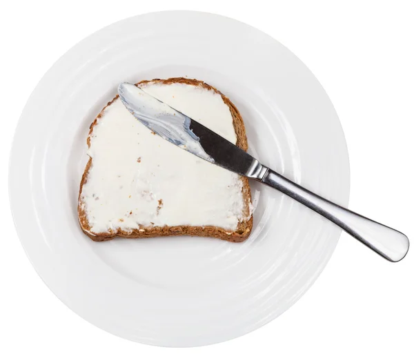 Above view of knife on bread with spread on plate — Stock Photo, Image