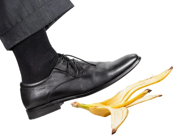 Нога в правой черной туфле поскользнулась на банановой кожуре — стоковое фото