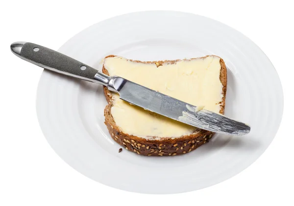 Grain bread and butter with table knife on plate — Stock Photo, Image