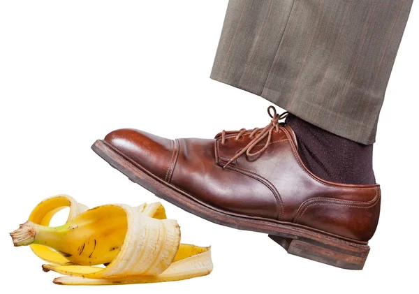 Bein im linken braunen Schuh rutscht auf eine Bananenschale — Stockfoto