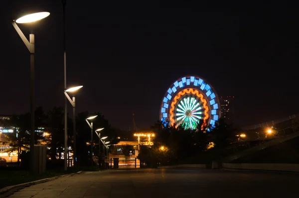 Uitzicht vanaf het steegje op nacht reuzenrad — Stockfoto