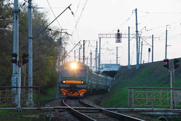 Vlak přijíždí na železniční přejezd ve městě — Stock fotografie