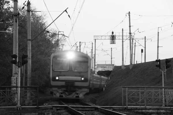 Treno arriva alla traversata ferroviaria in città in bianco e nero — Foto Stock