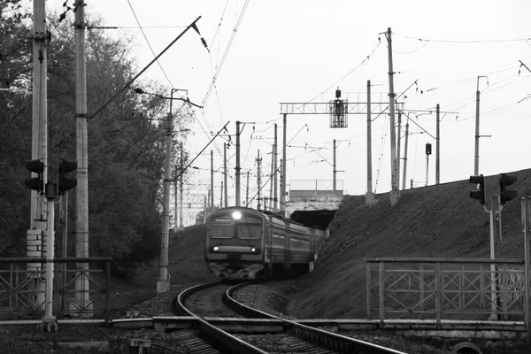 Vlak přijíždí na železniční přejezd ve městě černá a černobílá — Stock fotografie