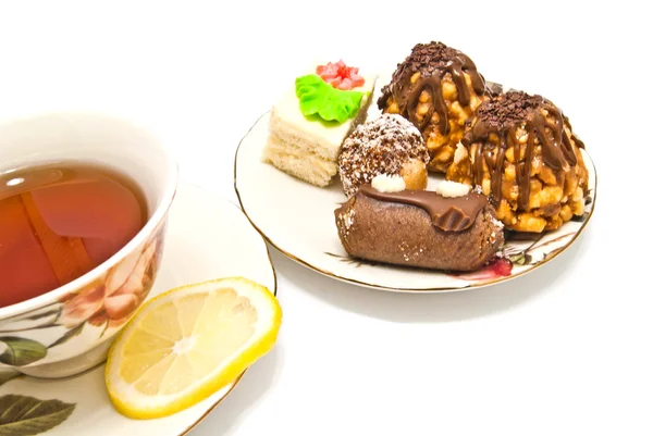 Different cakes and cup of tea on white — Stock Photo, Image