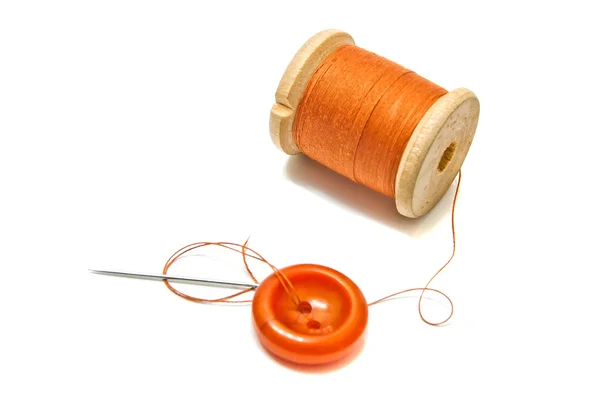 Bobina arancione di filo, e pulsante su bianco — Foto Stock