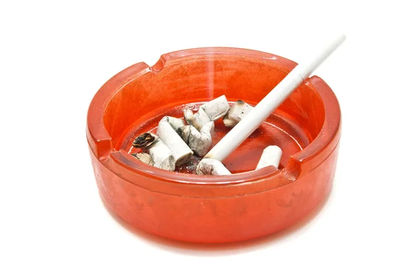 Butts and cigarette in glass ashtray — Stock Photo, Image