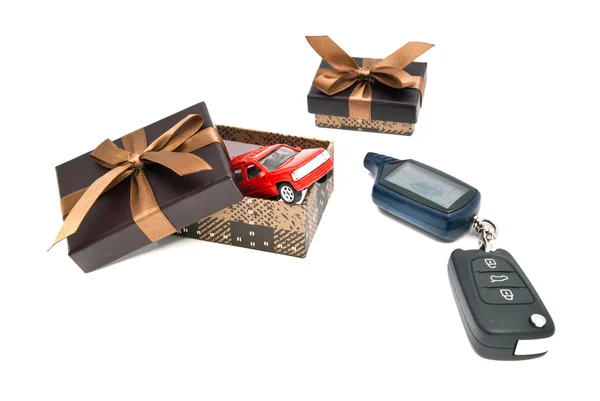 Red car, keys and brown gift boxes on white — Stock Photo, Image