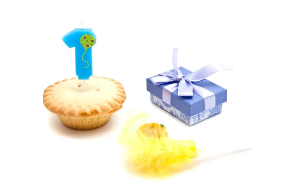 Кекс з однорічною свічкою на день народження, подарунком та свистом на білому — стокове фото