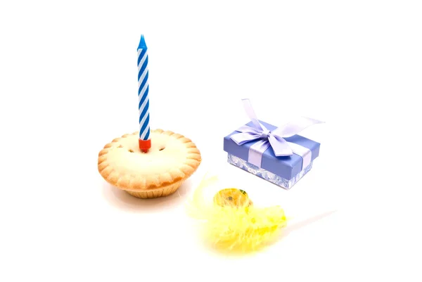 Cupcake with blue birthday candle, whistle and gift on white — Stock Photo, Image