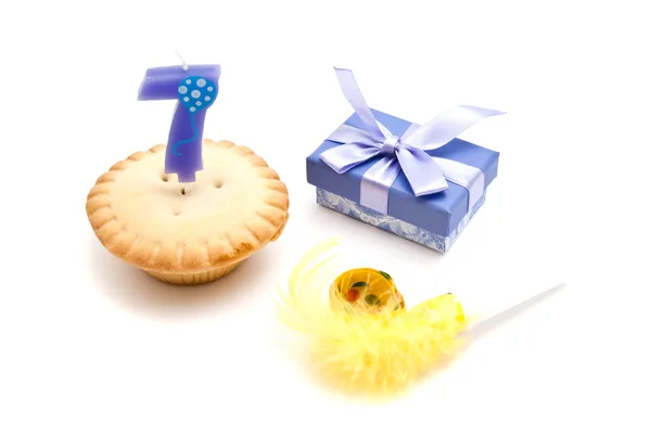 Cupcake with seven years birthday candle, gift and whistle on wh — Stock Photo, Image