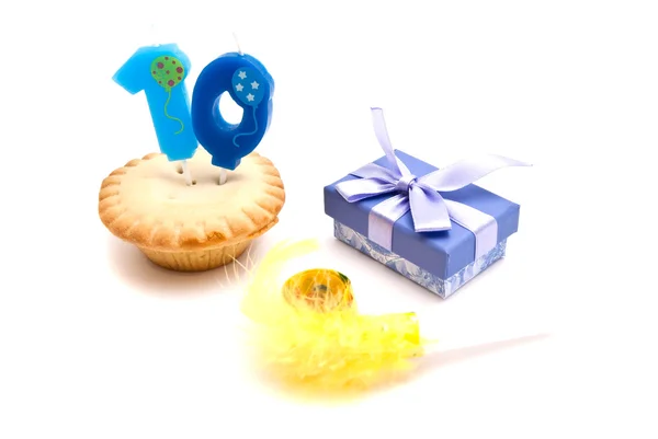 Cupcake with ten years birthday candle, gift and whistle on whit — Stock Photo, Image