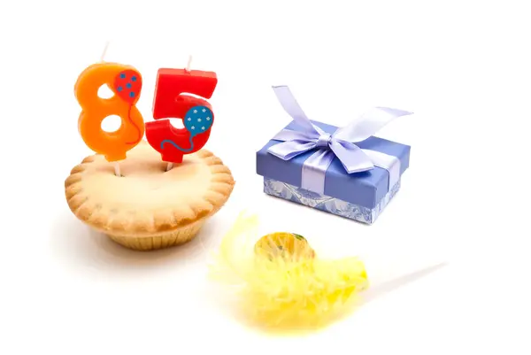 Cupcake with eighty five years birthday candle, gift and whistle — Stock Photo, Image