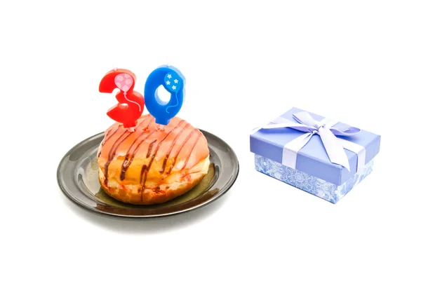 Donut met dertig jaar verjaardag kaars en gift op wit — Stockfoto