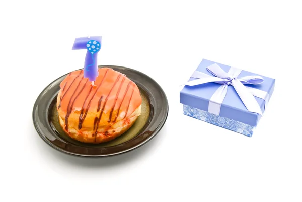 Donut com vela de aniversário de sete anos e presente no branco — Fotografia de Stock