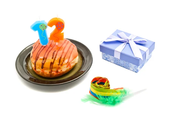 Donut with twelve years birthday candle, whistle and gift on whi — Stock Photo, Image