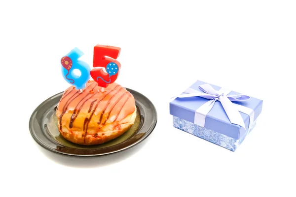 Donut avec soixante-cinq ans bougie d'anniversaire et cadeau — Photo