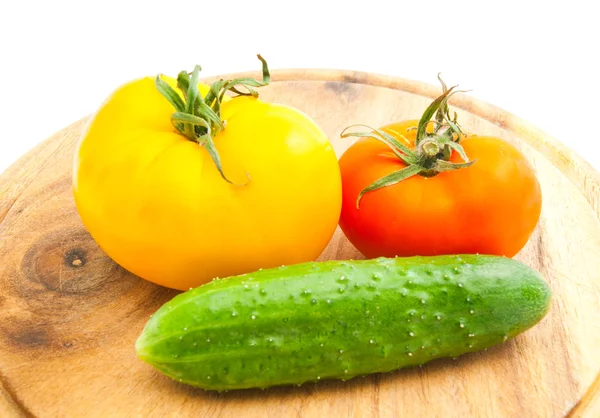 Tomatoes and cucumber on wooden cutting board — Stock Photo, Image