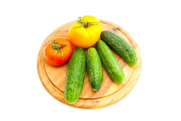 Pepinos e tomates em tábua de corte de madeira — Fotografia de Stock