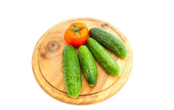 Cucumbers and tomato on cutting board — Stock Photo, Image
