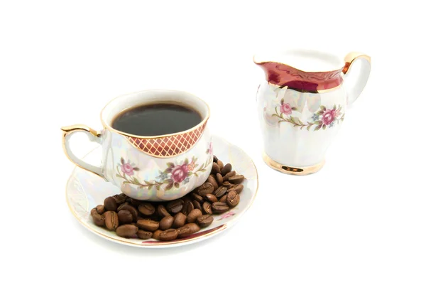 Кофейные зерна, молочный кувшин и чашка кофе — стоковое фото