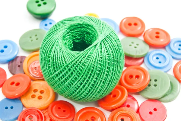 Green ball of thread and colored buttons — Stock Photo, Image