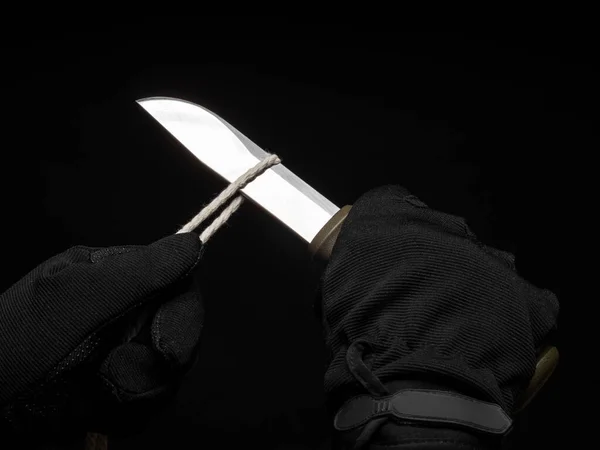 Hands in black gloves cut the rope with a fixed blade sharp knife — Stock Photo, Image