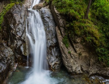 Bir vadide yürürken kayalar ve çalılarla dolu güzel bir şelale.