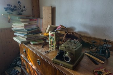 Terk edilmiş bir evde eski projektör ve kitaplar