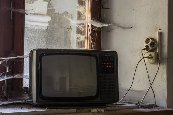 放棄された家にクモの巣がある窓辺の古いテレビ — ストック写真
