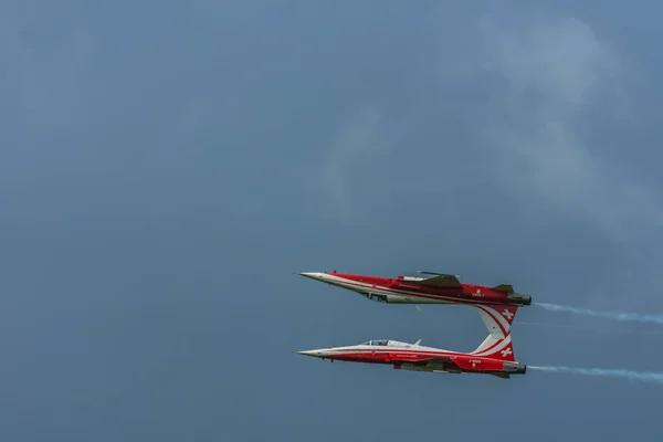 航空ショーで赤と白の2機の飛行機が互いの上側を飛びます — ストック写真