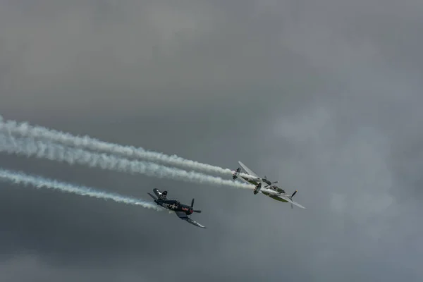 Két Propeller Repülőgép Füsttel Miközben Sűrű Esőfelhők Egy Légi Bemutatón — Stock Fotó