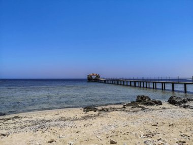 Mısırda mavi gökyüzü olan kumlu sahilde uzun bir iskele.