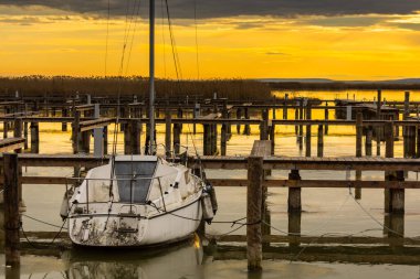 Gün batımında göl kenarında tek bir beyaz tekne.
