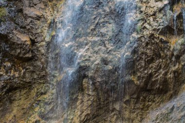 fine waterfall and steep rocks while hiking in the mountains in the summer