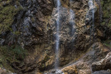 fine little waterfall over rugged rock in the mountains while hiking