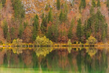 Dağlardaki çalılar ve ağaçlar göldeki renkli yansımalarla 
