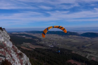 Dağlarda yürüyüş yaparken geniş manzaralı tek turuncu mavi paraglider