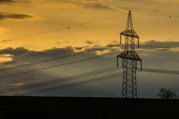 Elektrický Sloup Barevnými Žlutými Mraky Obloze Černými Poli Při Západu — Stock fotografie