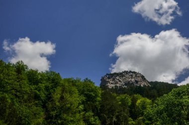 Mavi gökyüzünde beyaz bulutlar ve yürüyüş yaparken güzel dağlar.