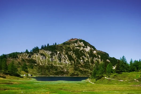 深い青い空の山の上にトレイルとケーブルカーがある山の湖 — ストック写真