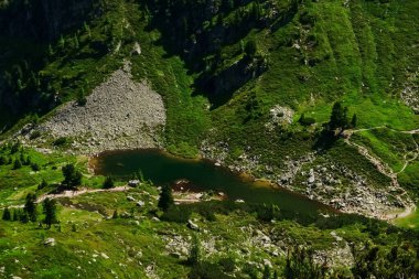 Dağ gölü yeşil bir arazide, yukarıdan detaylı bir görünüm alırken.